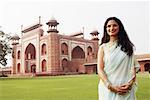 Portrait of a young woman standing in front of a mausoleum, Taj Mahal, Agra, Uttar Pradesh, India