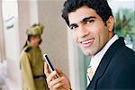 Portrait d'un homme d'affaires détenant un téléphone mobile et souriant