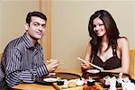 Portrait of a young couple eating Japanese food and smiling