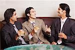 Close-up of three businessmen holding glasses of whiskey