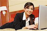 Portrait of a businesswoman lying on the bed and using a laptop