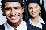 Portrait of a male graduate smiling with a female graduate behind him