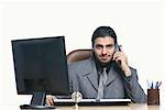 Portrait of a businessman talking on a cordless phone in front of a computer