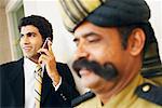Businessman talking on a mobile phone behind a security guard