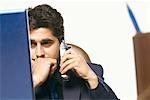 Gros plan d'un homme d'affaires parlant sur un téléphone sans fil en face d'un ordinateur portable