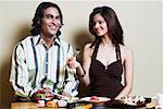 Portrait d'un jeune homme assis avec une jeune femme lors d'une table à manger et souriant