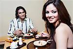 Portrait of a young woman sitting with a young man at the dining table and smiling