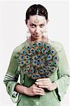 Portrait of a young woman holding a peacock feather fan