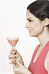 Profil de côté d'une jeune femme tenant un verre de martini