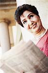 Mature woman holding a newspaper and smiling