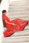 Side profile of a young woman sitting on the staircase and smiling