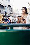 Young man sitting in a rickshaw and holding a mobile phone