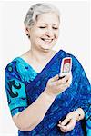 Gros plan d'une femme d'âge mûr en souriant et en regardant un téléphone mobile