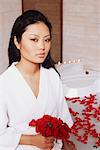 Portrait of a young woman holding a bunch of roses near a bathtub