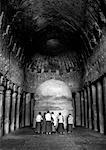 Rear view of Monks praying in front of a sculpture, Kanari Cave Mumbai, Maharashtra, India