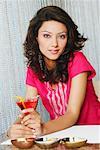 Portrait d'une jeune femme assise dans un restaurant et tenant un verre de martini