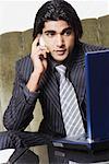 Businessman sitting in front of a laptop and talking on a mobile phone