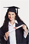 Portrait of a female graduate holding a diploma and smiling