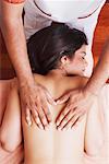 High angle view of a naked young woman getting a back massage from a massage therapist