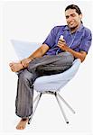 Young man sitting on a chair and listening to an MP3 player