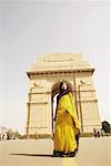 Vue d'angle faible d'une jeune femme debout devant un monument, porte de l'Inde, New Delhi, Inde