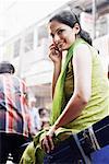 Side profile of a young woman sitting in a rickshaw talking on a mobile phone