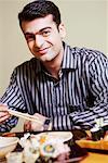 Portrait of a young man sitting at the dining table and smirking