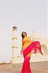Close-up of a young woman standing in front of a mausoleum, Taj Mahal, Agra, Uttar Pradesh, India
