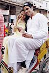 Portrait of a young couple sitting in a rickshaw and listening to an MP3 player