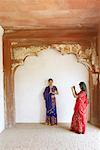 Junge Frau fotografieren ihrer Freundin stehen in einem Gebet Stellung, Agra Fort, Agra, Uttar Pradesh, Indien