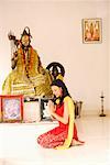 Side profile of a young woman praying in front of an idol of Lord Shiva