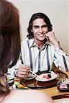 Close-up of a young man and a woman sitting at the dining table