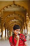 Portrait d'une jeune femme souriante avec son doigt sur ses lèvres, Fort d'Agra, Agra, Uttar Pradesh, Inde