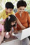 Close-up of a mature woman and her two grandchildren looking at a laptop