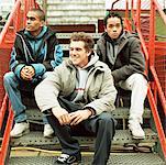 Trois jeunes hommes assis sur les escaliers