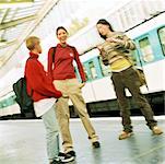 Three teenagers standing on subway platform, blurred