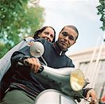 Young man and young woman on motor scooter, waist up, tilt