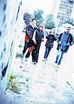 Group of young people walking together on sidewalk.