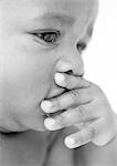 Baby with hand over mouth, close-up, b&w