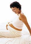 Pregnant woman sitting with hand on stomach, smiling