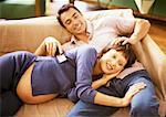 Homme et une femme enceinte sur canapé, couché sur les genoux de l'homme, contrôle à distance holding homme, portrait de femme