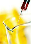 Syringe above glass flask, close-up