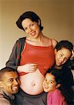 Man and children around pregnant woman's exposed stomach