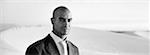 Businessman in front of dunes, b&w, panoramic view