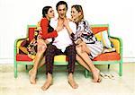 Man sitting on sofa being caressed by two women.