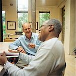 Two mature men sitting at table, laughing