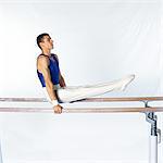 Young male gymnast on parallel bars, side view