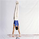 Jeune gymnaste masculin effectuant de routine sur les barres parallèles, vue arrière