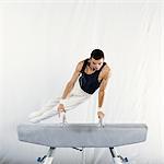 Young male gymnast performing routine on pommel horse