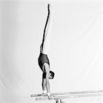 Young male gymnast doing handstand on parallel bars, side view